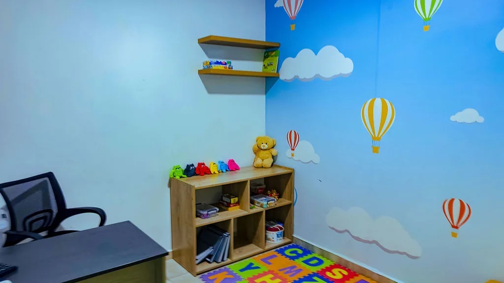 Aula con el mural de globos aerostáticos y los estantes de juguetes